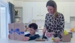 Mother and child in kitchen preparing a meal from a Hellmann’s recipe book.