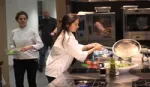 Women chef in industrial kitchen creating and serving a plant-based dish