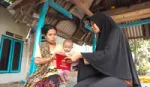 Mother holding a baby being shown a brochure by another woman